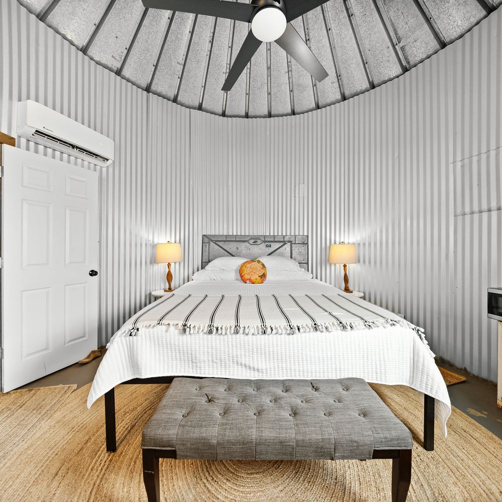 The silo bedroom — a bed against the curved corrugated-steel wall